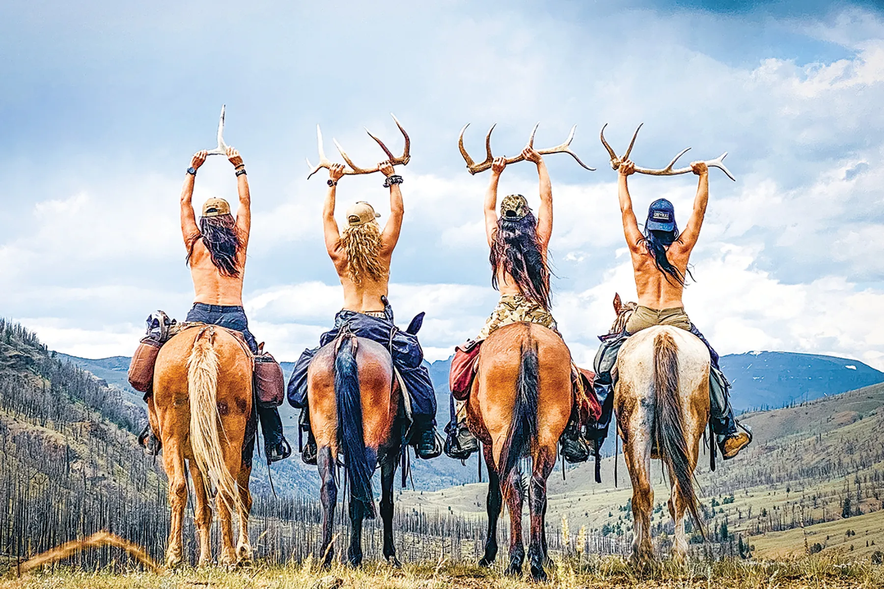 four women on horseback holding elk antlers above their heads