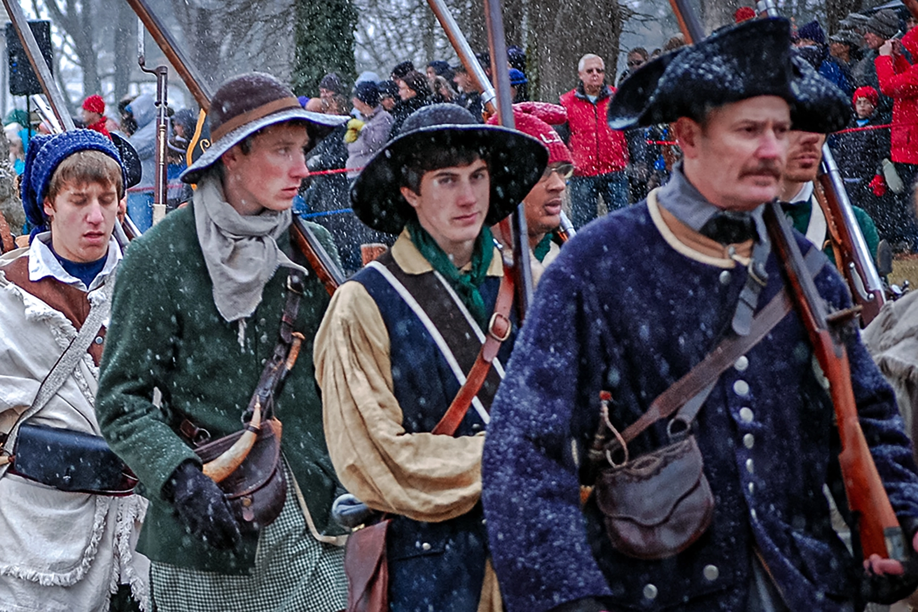 reenactors recreating washington's crossing of the delaware river. The man in the back can be seen wearing a recreation of a liberty cap.