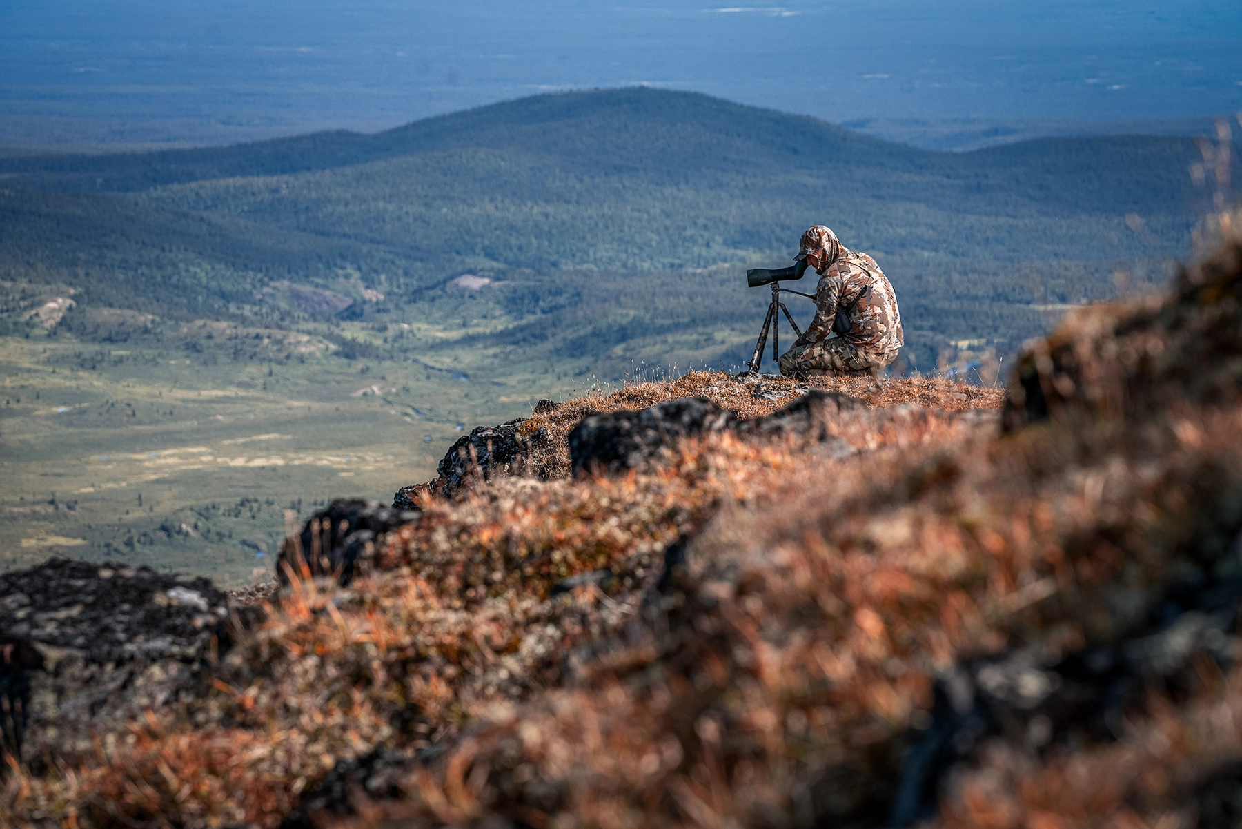 a hunter glassing on a cliff