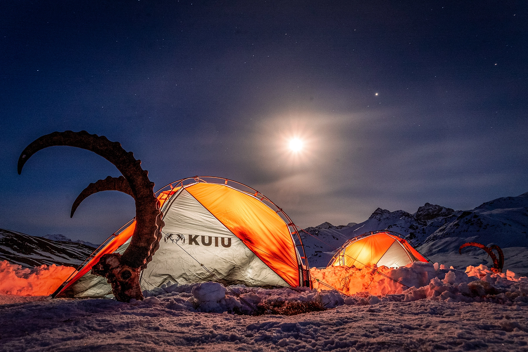 sheep horns and skull stuck in the snow outside of two kuiu tents in the snow