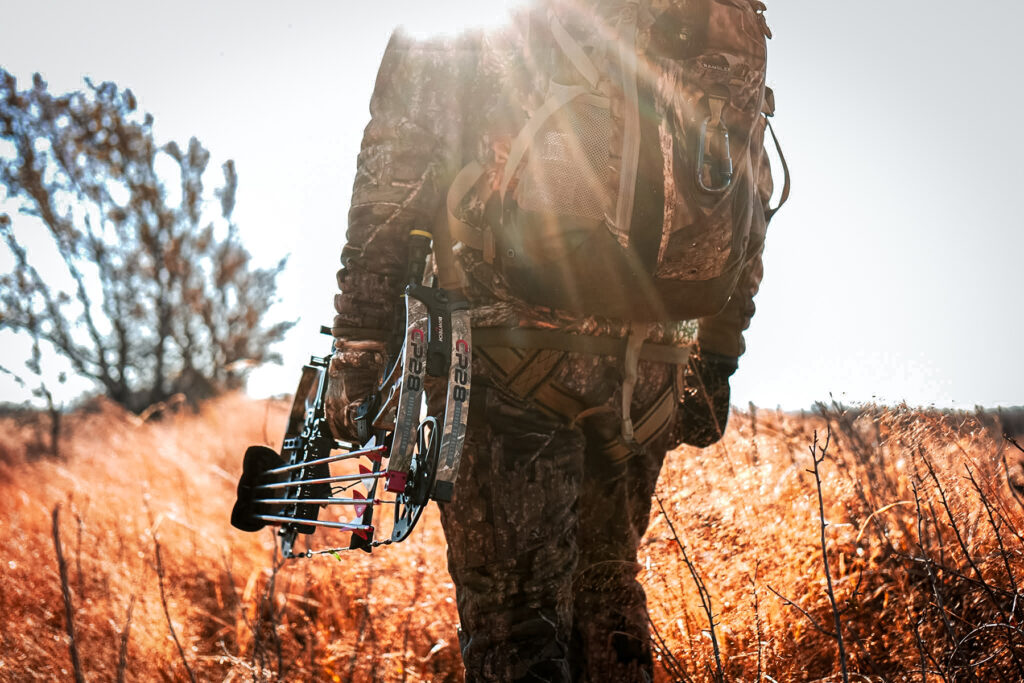 Bowhunter standing in a field with the sun in the background Bowtech