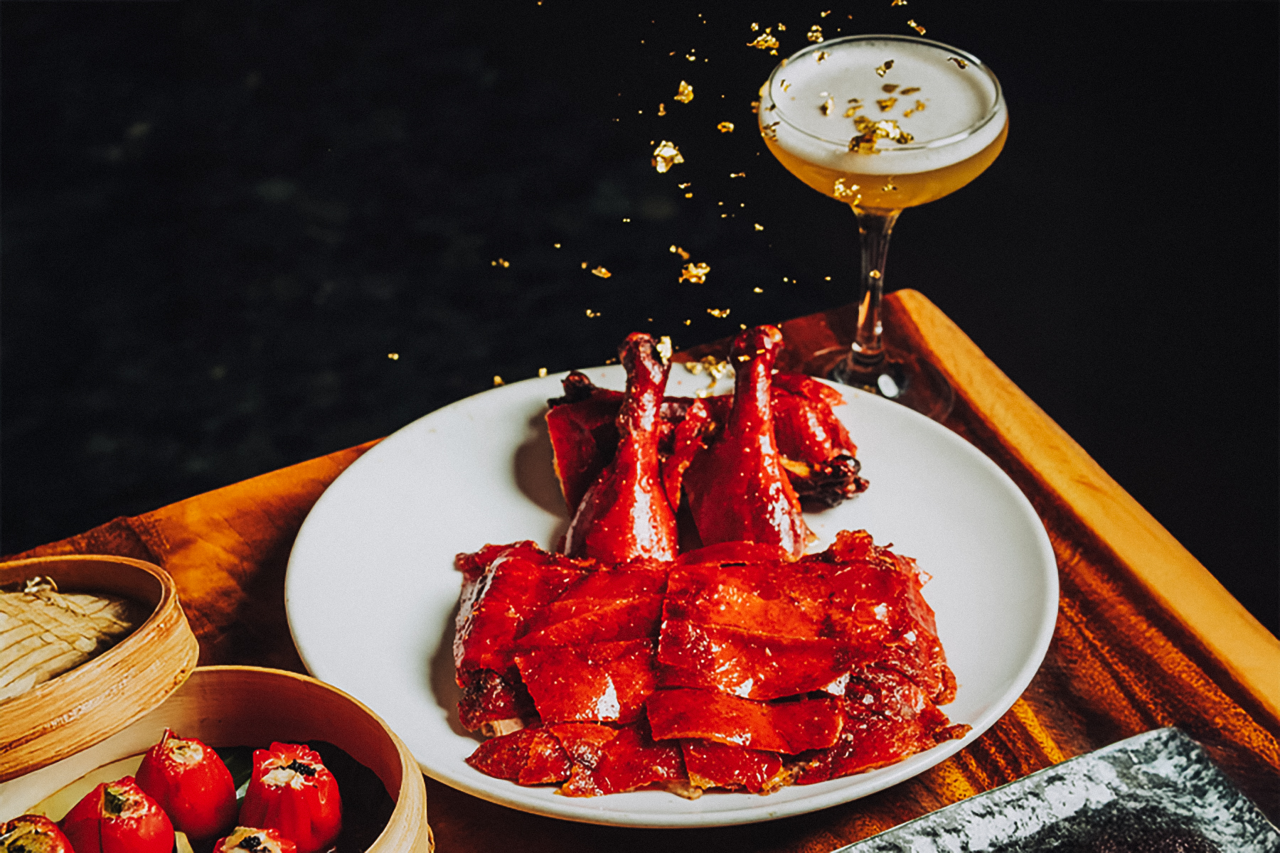 Peking Duck on a plate with a cocktail and dumplings