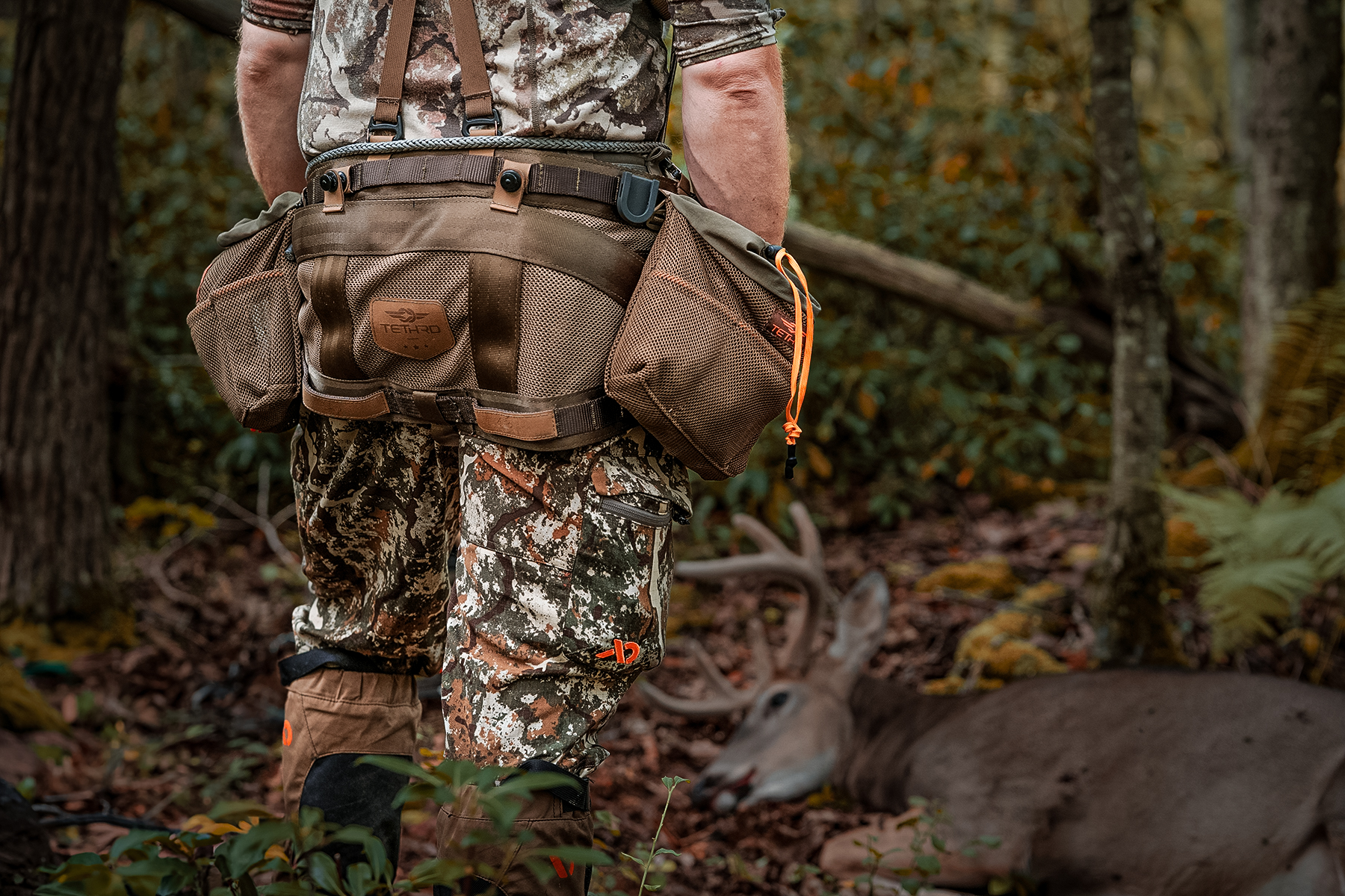a hunter wearing his hunting saddle next to a nice buck