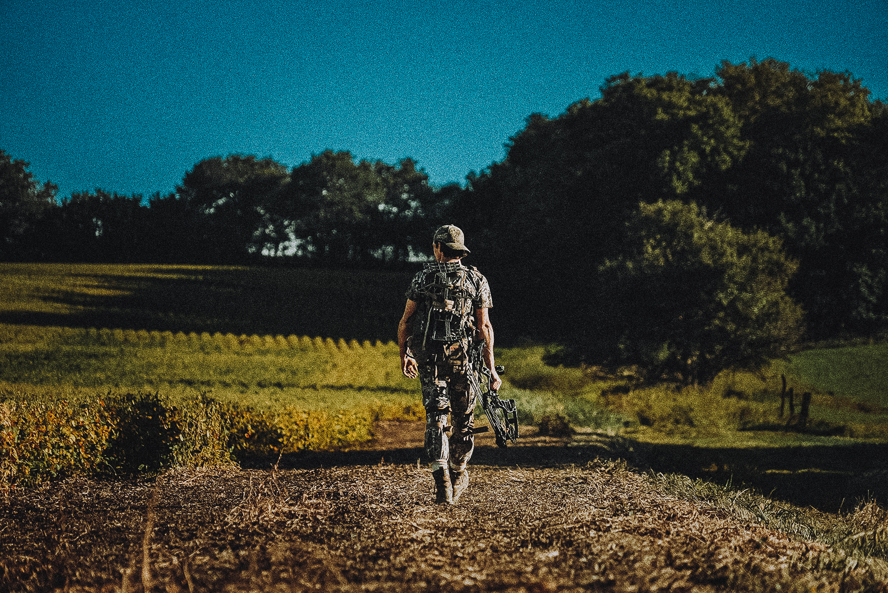a bowhunter hiking in with his hunting saddle on his back