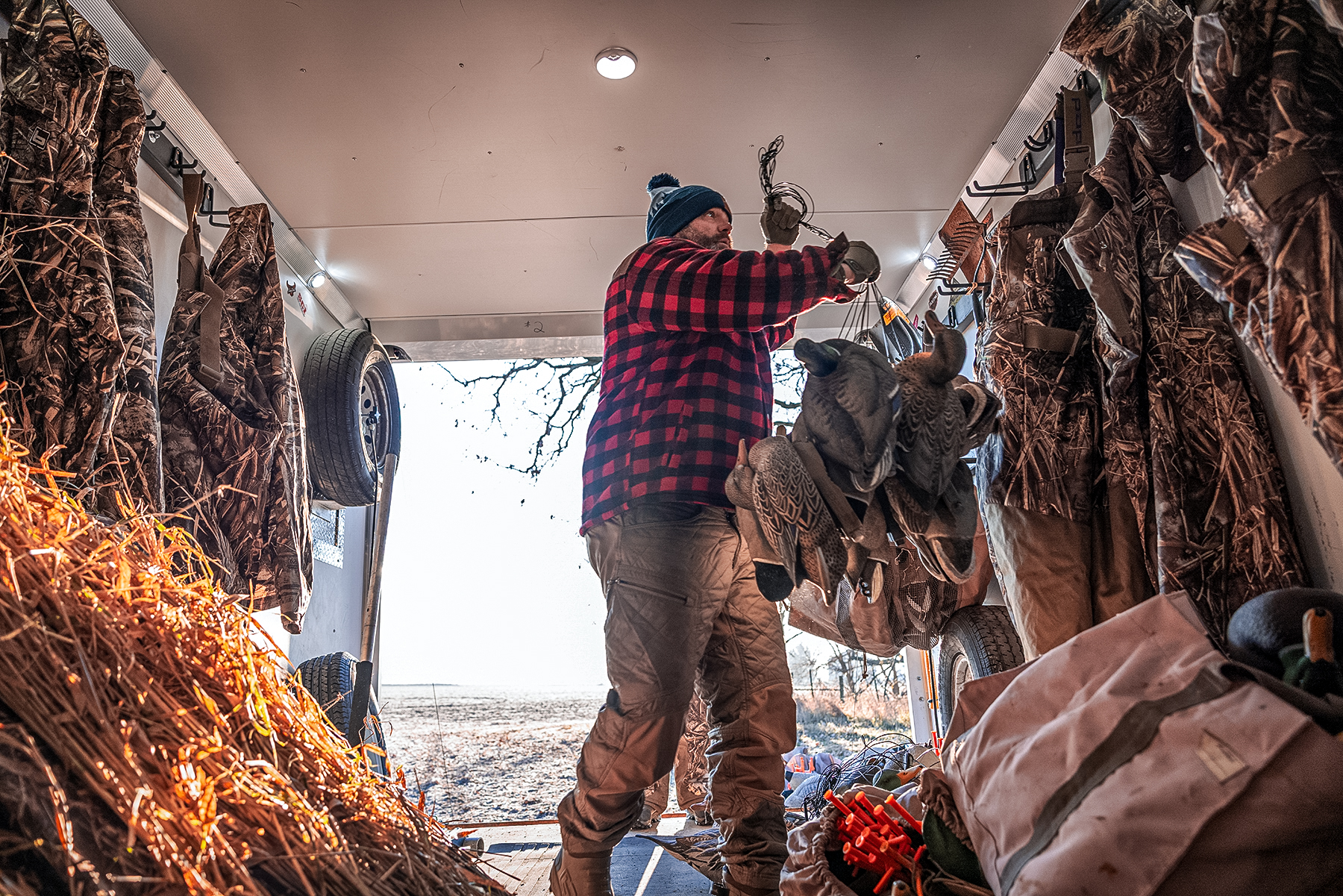 chad belding in his duck hunting trailer hanging some dekes