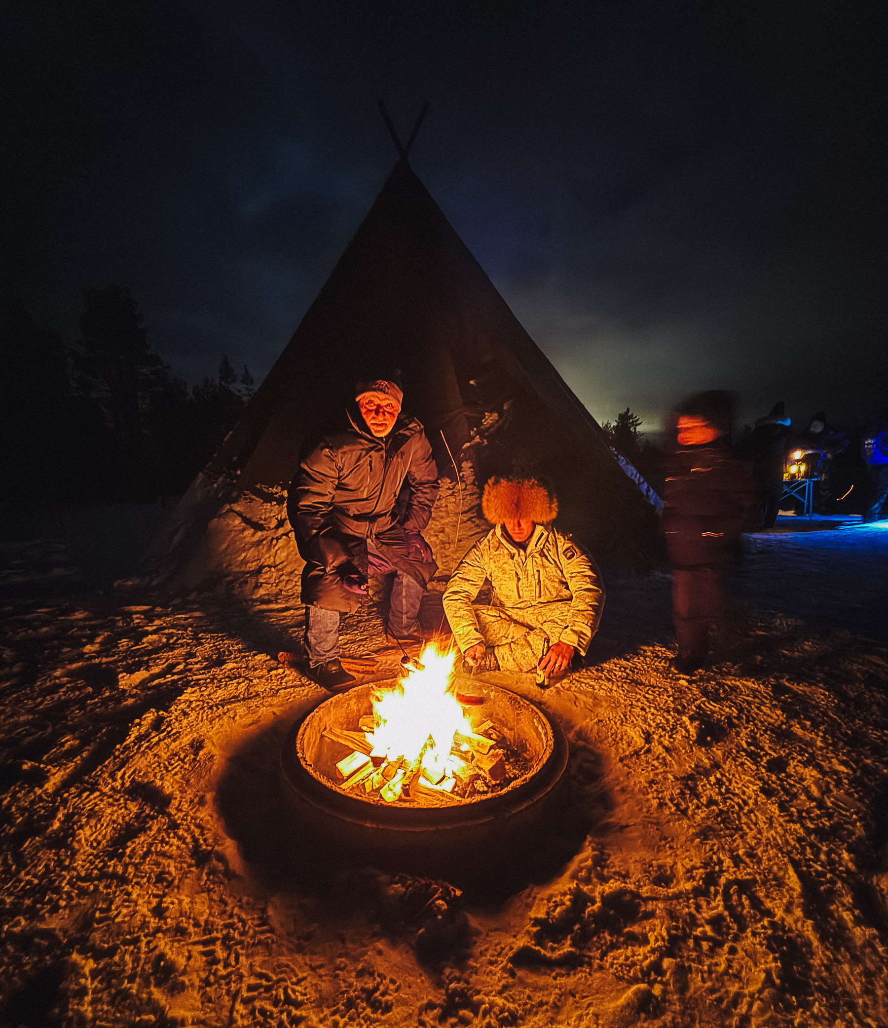 a campfire by a tend in the snow