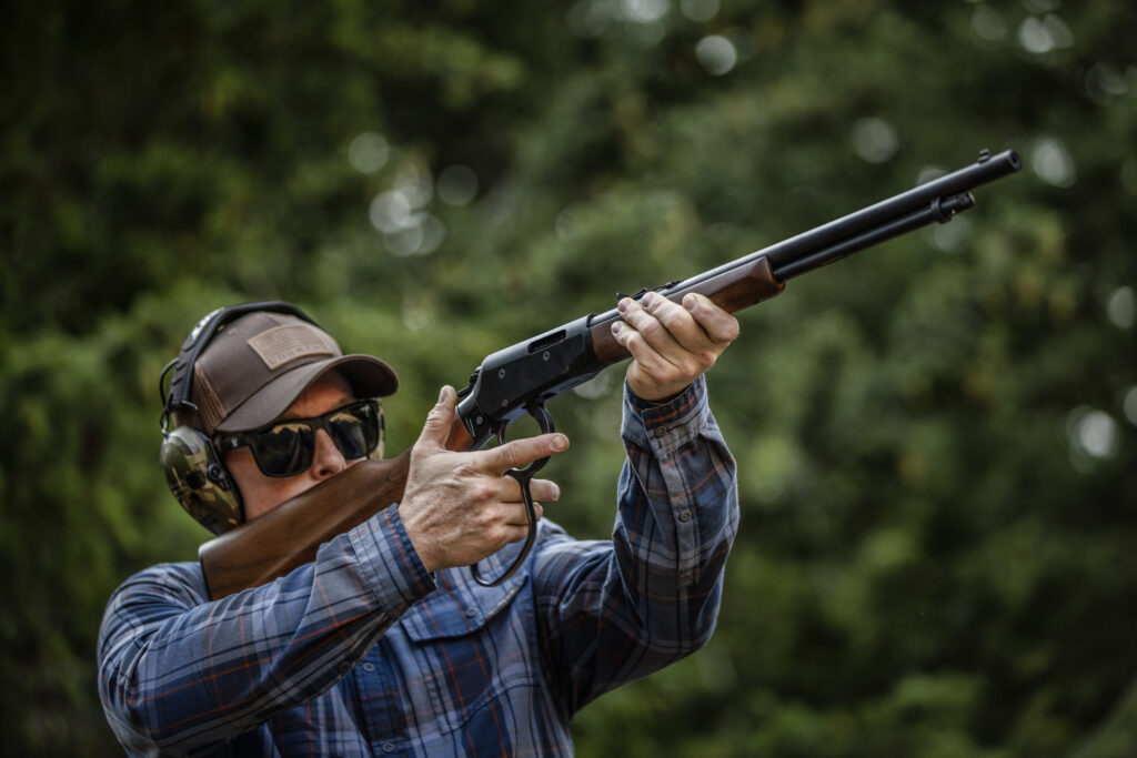 A man shoulders a lever action rifle. The Savage REVEL Classic. 