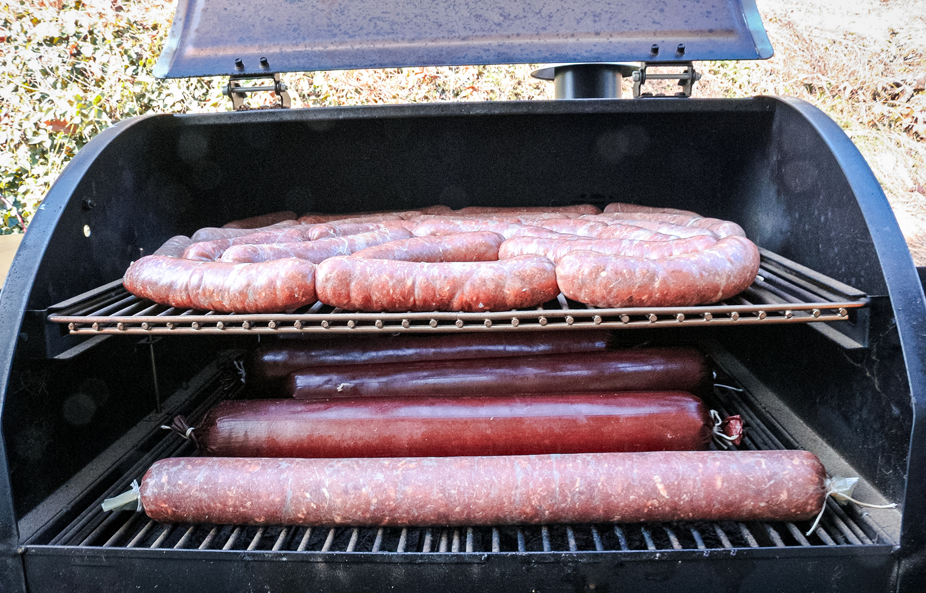four types of sausage in a smoker