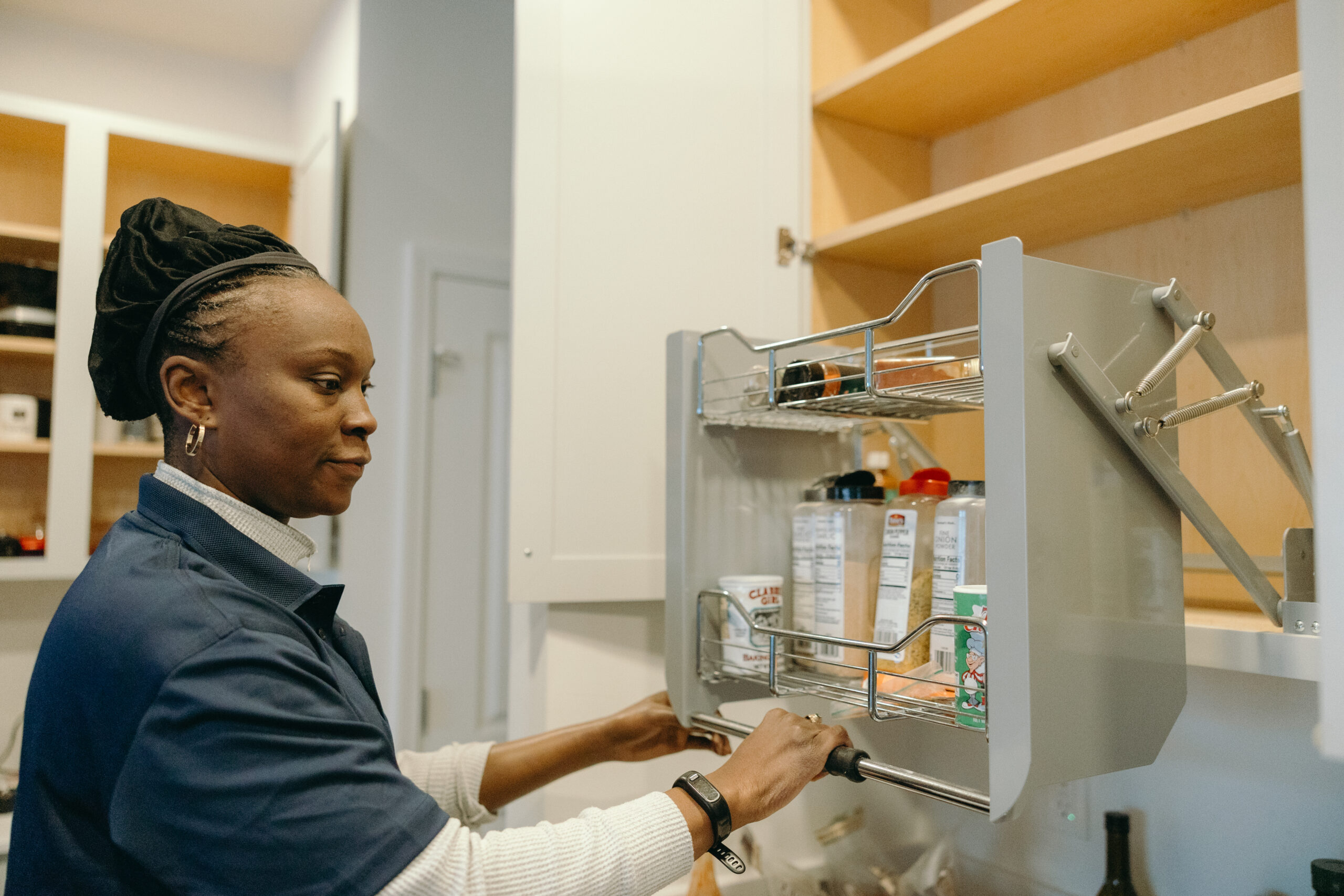 A woman demonstrates a kitchen's pull-down shelves.