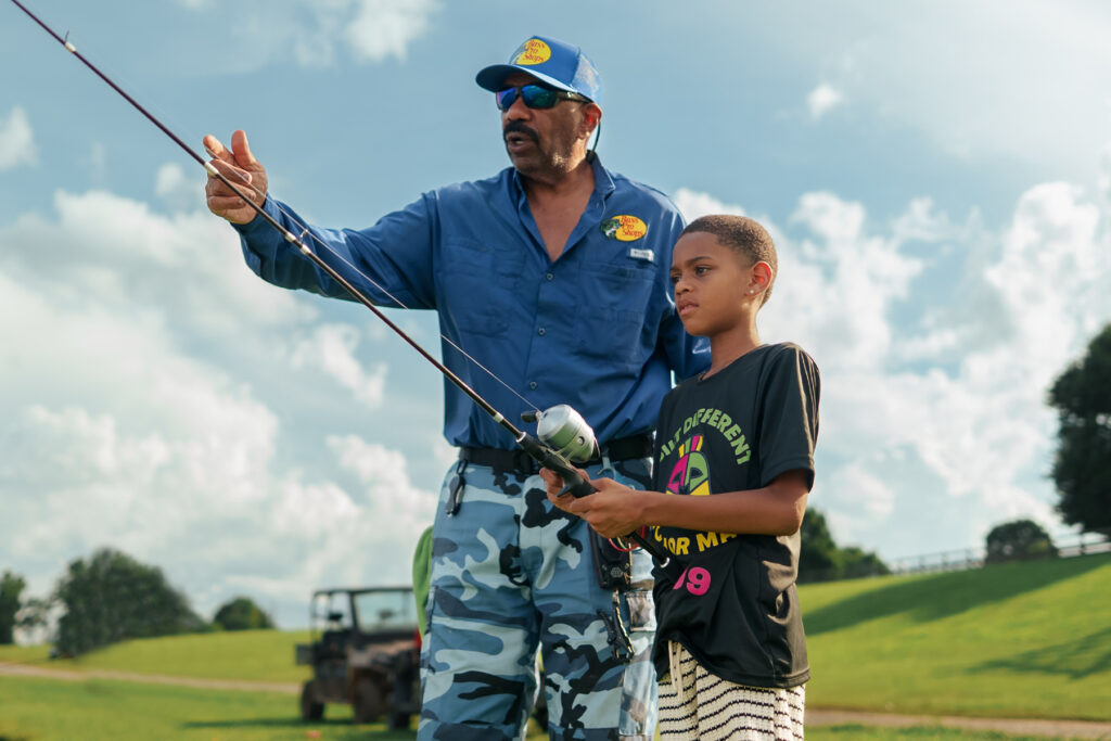 Steve Harvey teaching one of his mentees how to bass fish