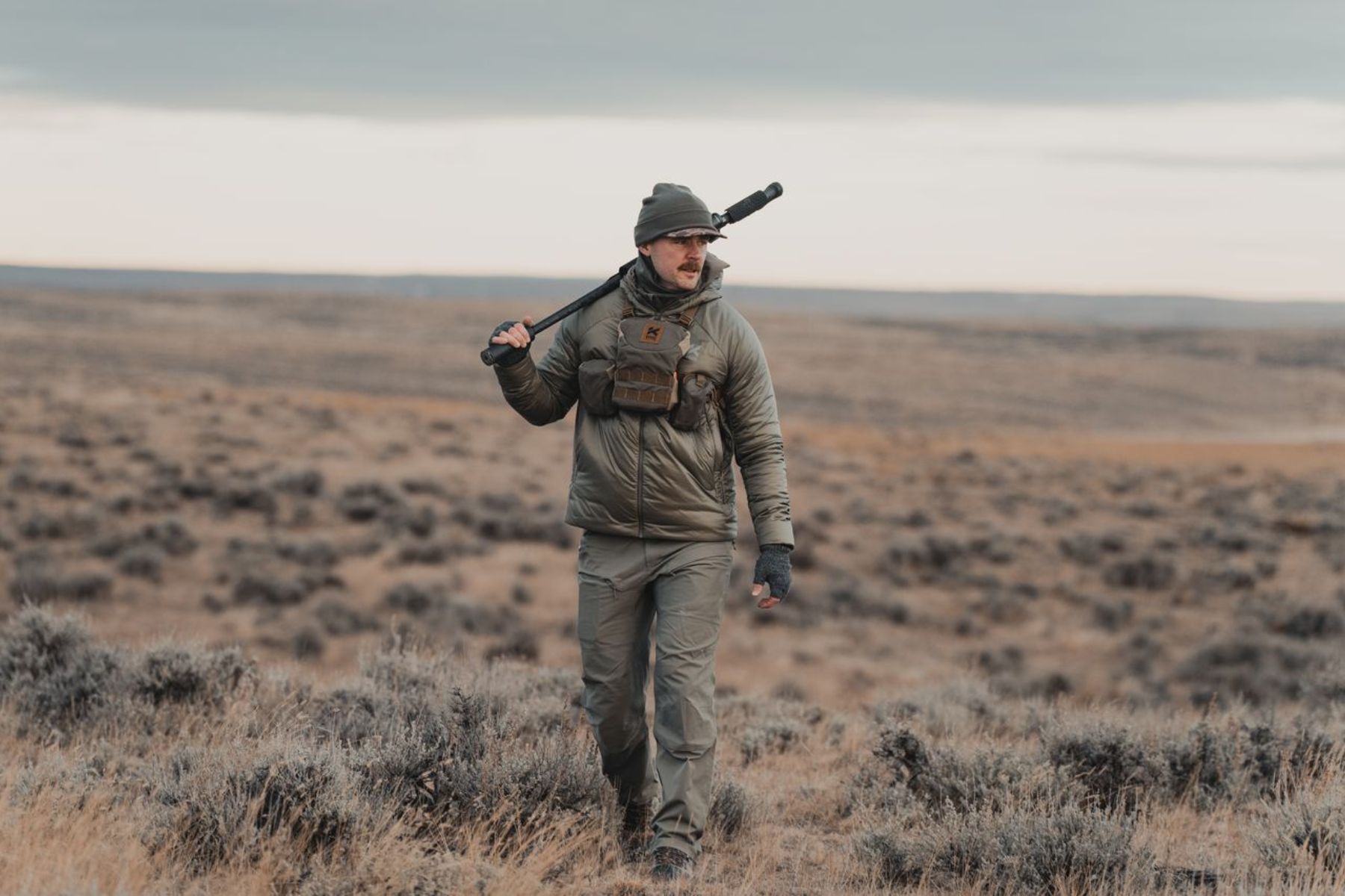 A hunter dressed Kifaru apparel walks across the prairie.