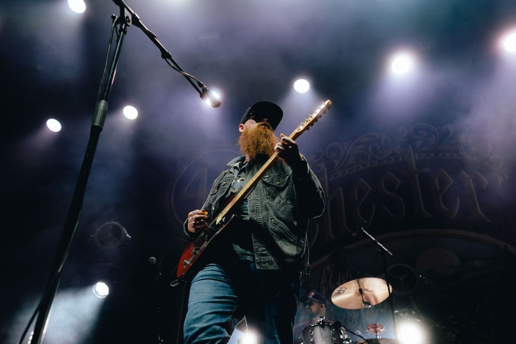 A bearded man plays guitar on stage.