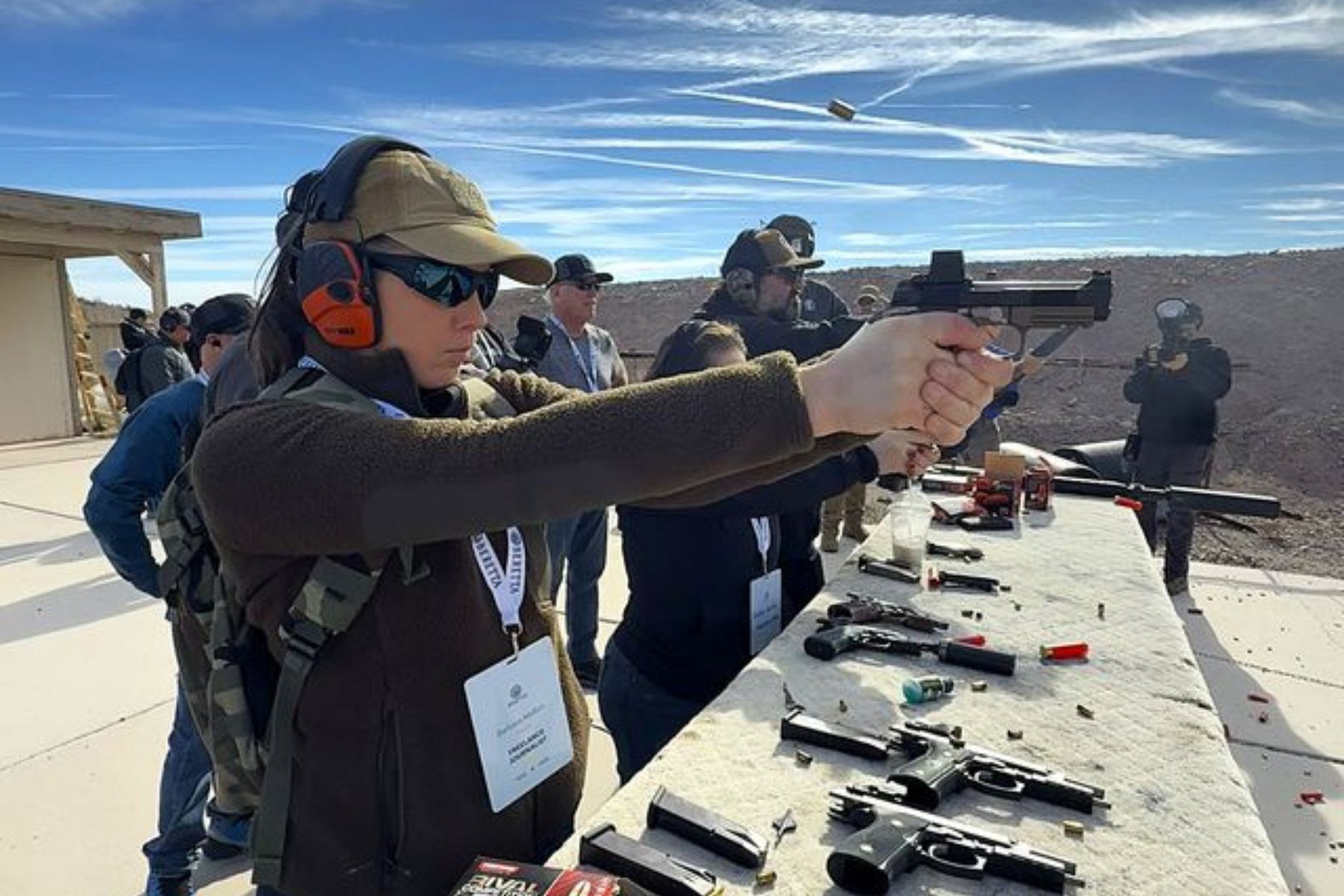 A female shooter shoots a new Beretta handgun at range day.