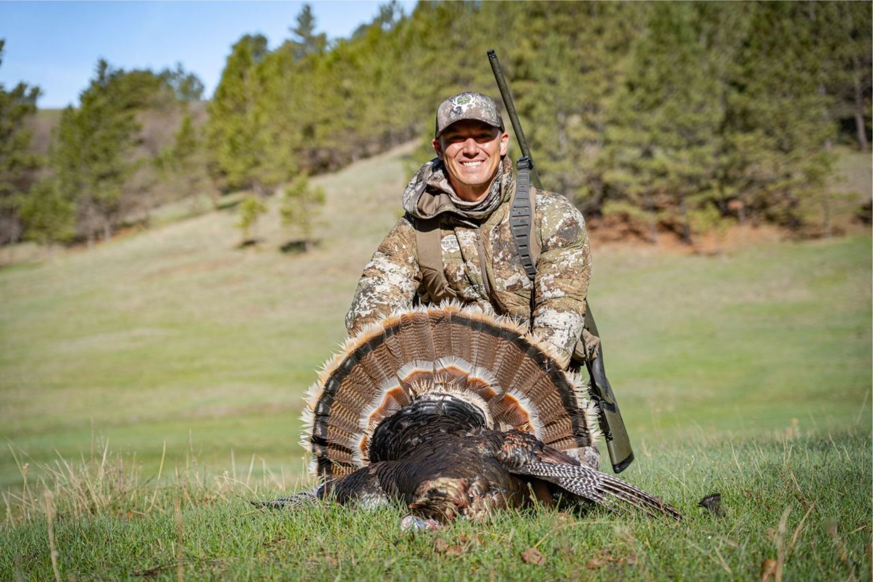A hunter poses with a shotgun and a turkey