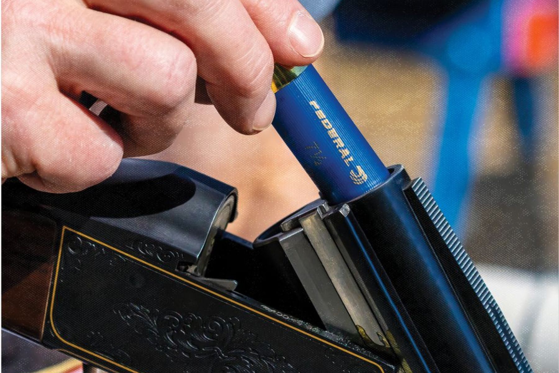 a hand loads a shotshell in an over/under shotgun