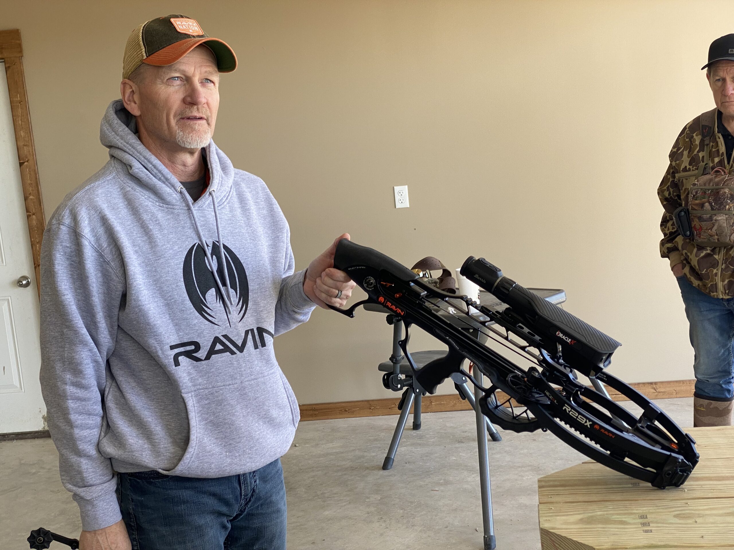A man in a hoodie holds a Ravin crossbow.