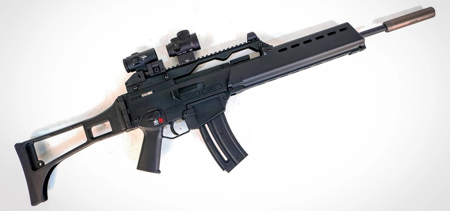 the rifle topped with a Trijicon red dot and magnifier