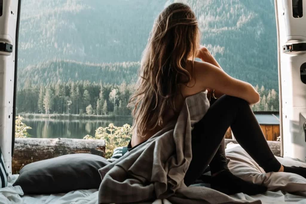 Woman parked in her van overlooking mountain lake