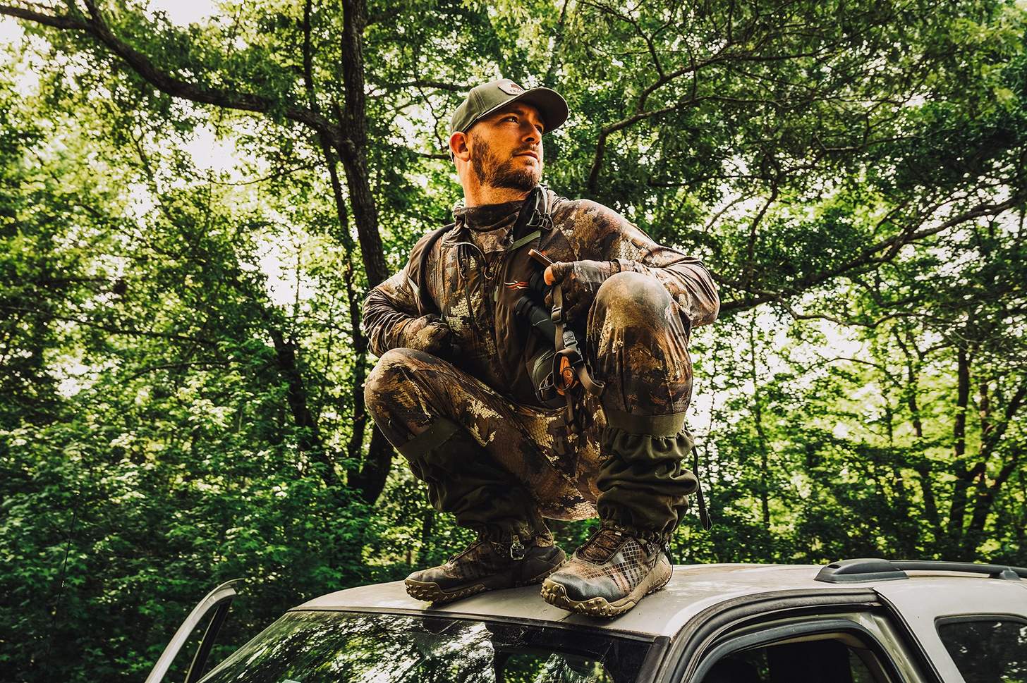 a hunter squatting on the roof of a truck