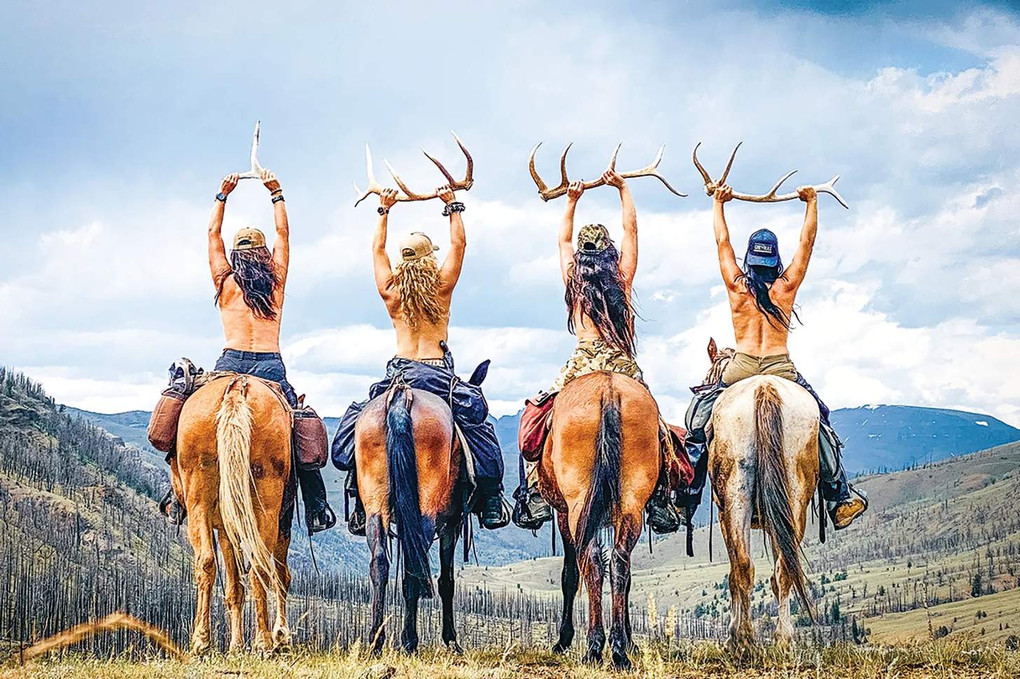 four women on horseback holding elk antlers above their heads