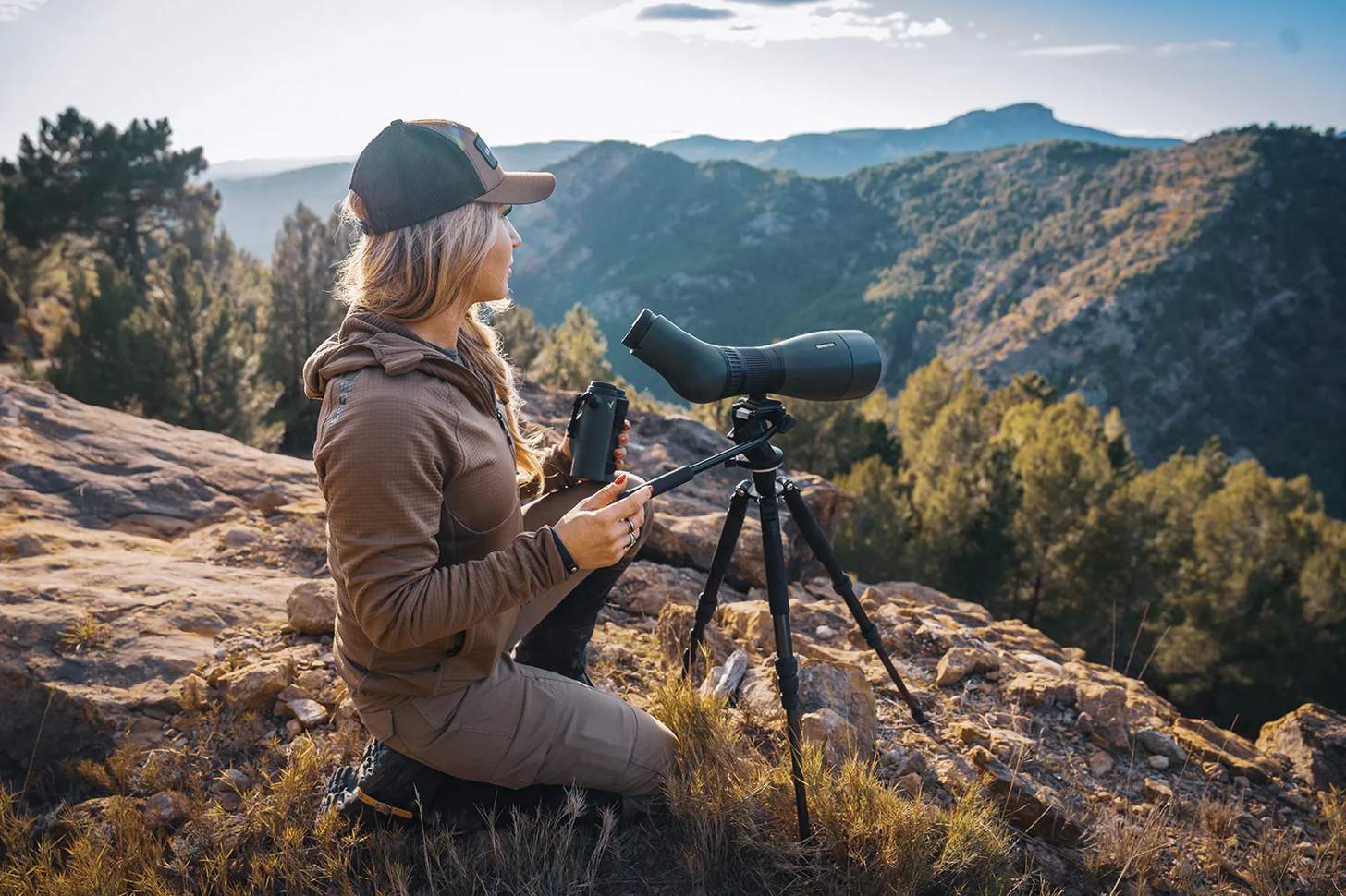 Amanda Caldwell glassing from a knoll with a spotting scope on a tripod
