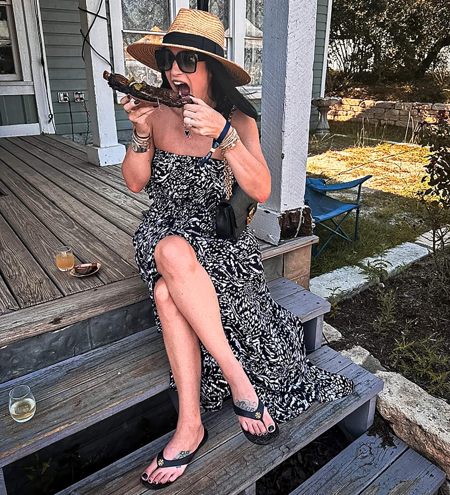 woman eating a large beef rib on a stoop
