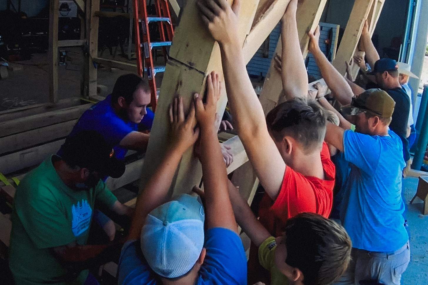 a group of men and kids raising a wooden frame