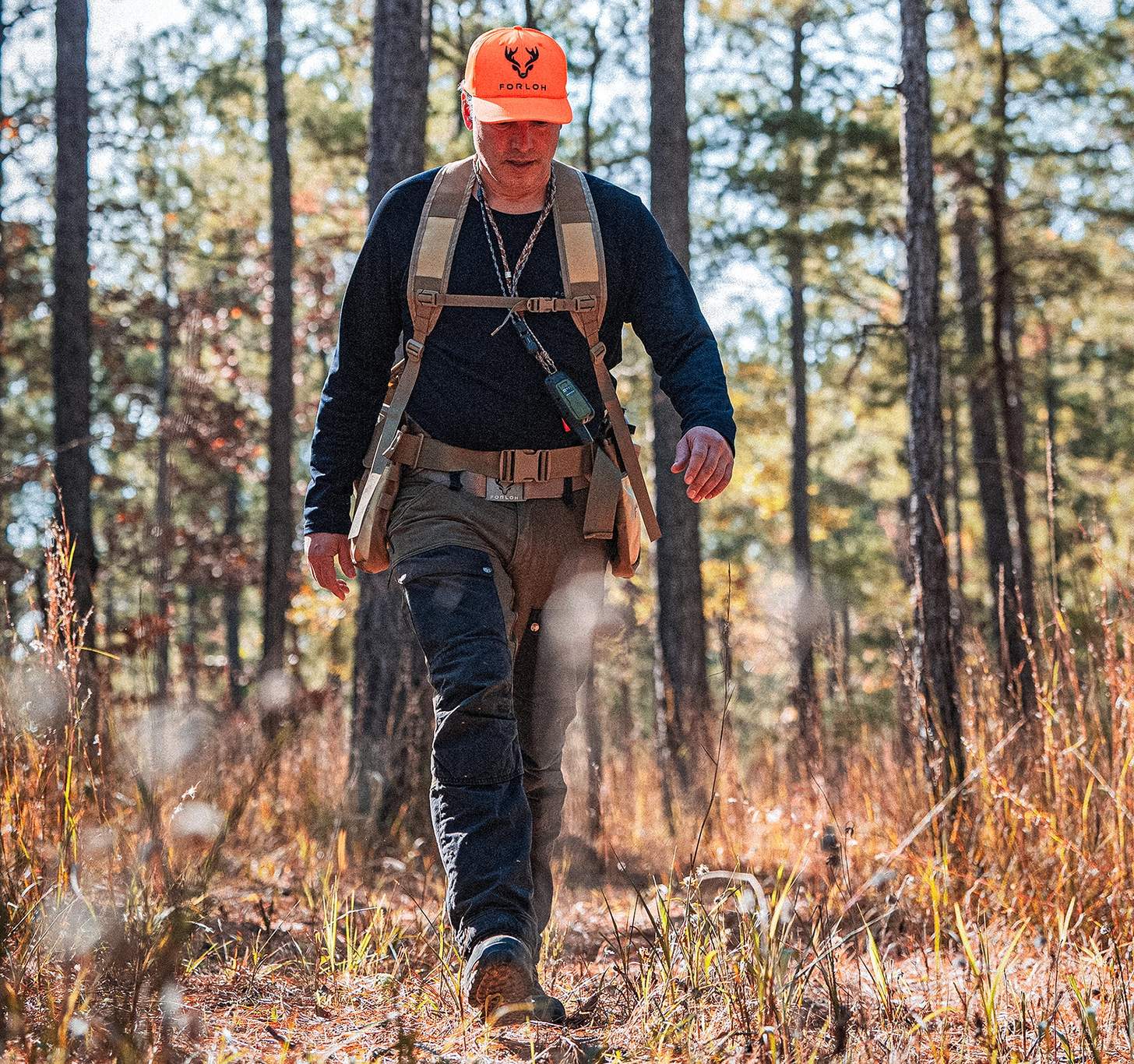 a man in a FORLOH hat and a pack hiking in the woods