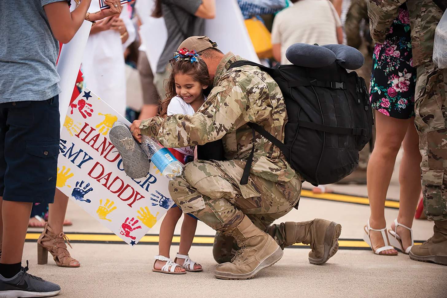 A member of the U.S. military hugs his daughter after returning home from deployment. 