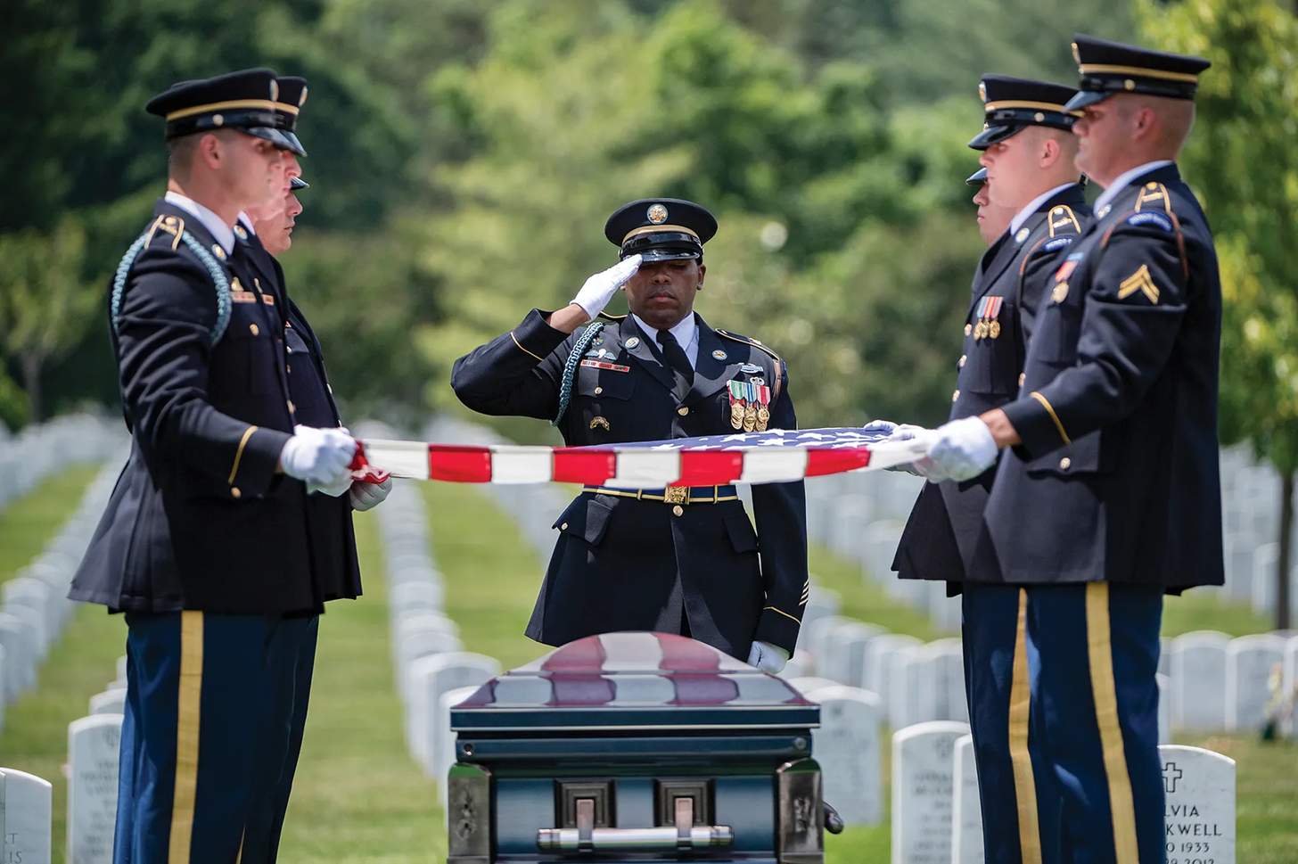 US Army soldiers folding an American flag over a casket at a veteran's cemetery. 