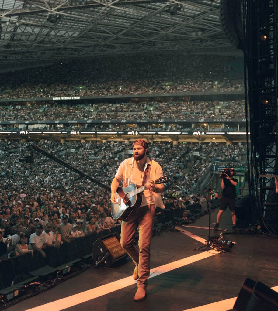Jordan Davis playing guitar on stage at a stadium show