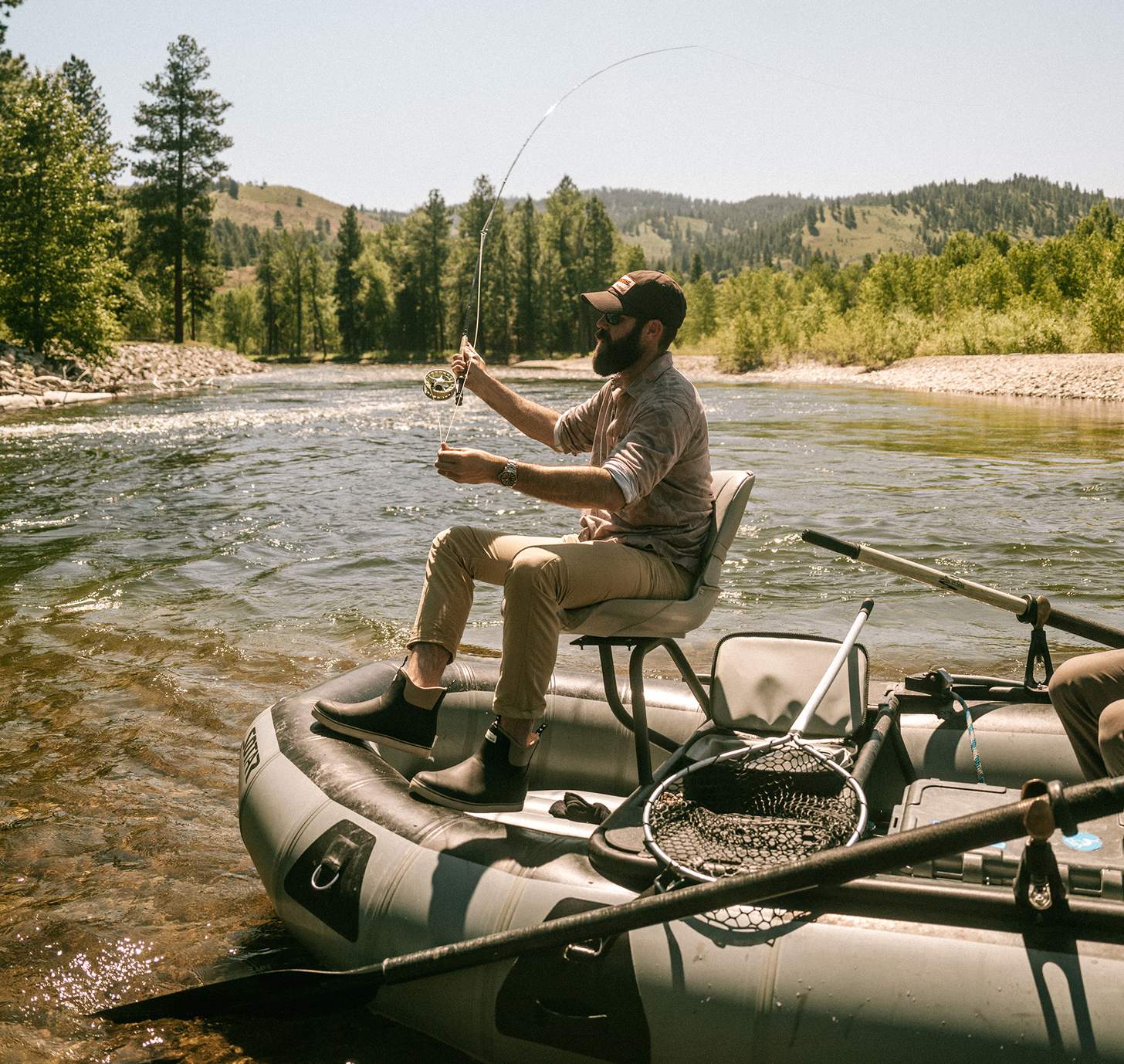 Jordan Davis fly fishing in the mountains on a raft