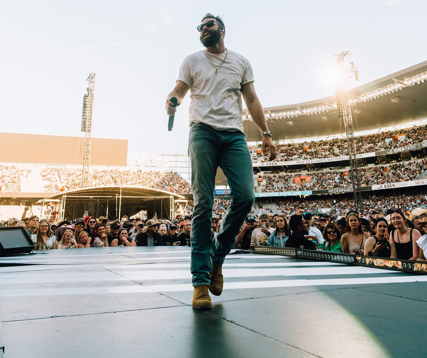 Jordan Davis sings on stage at a packed stadium show