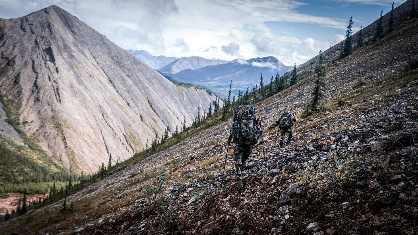 two hunters packing out sheep on a steep slope