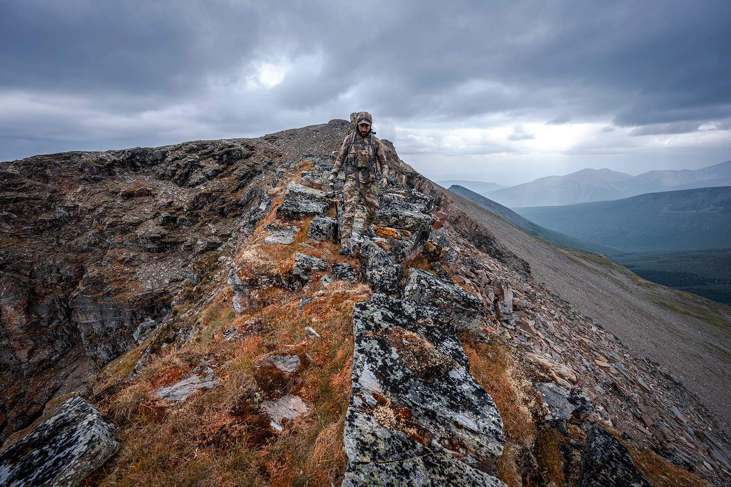 a hunter in KUIU camo descends a steep ridge