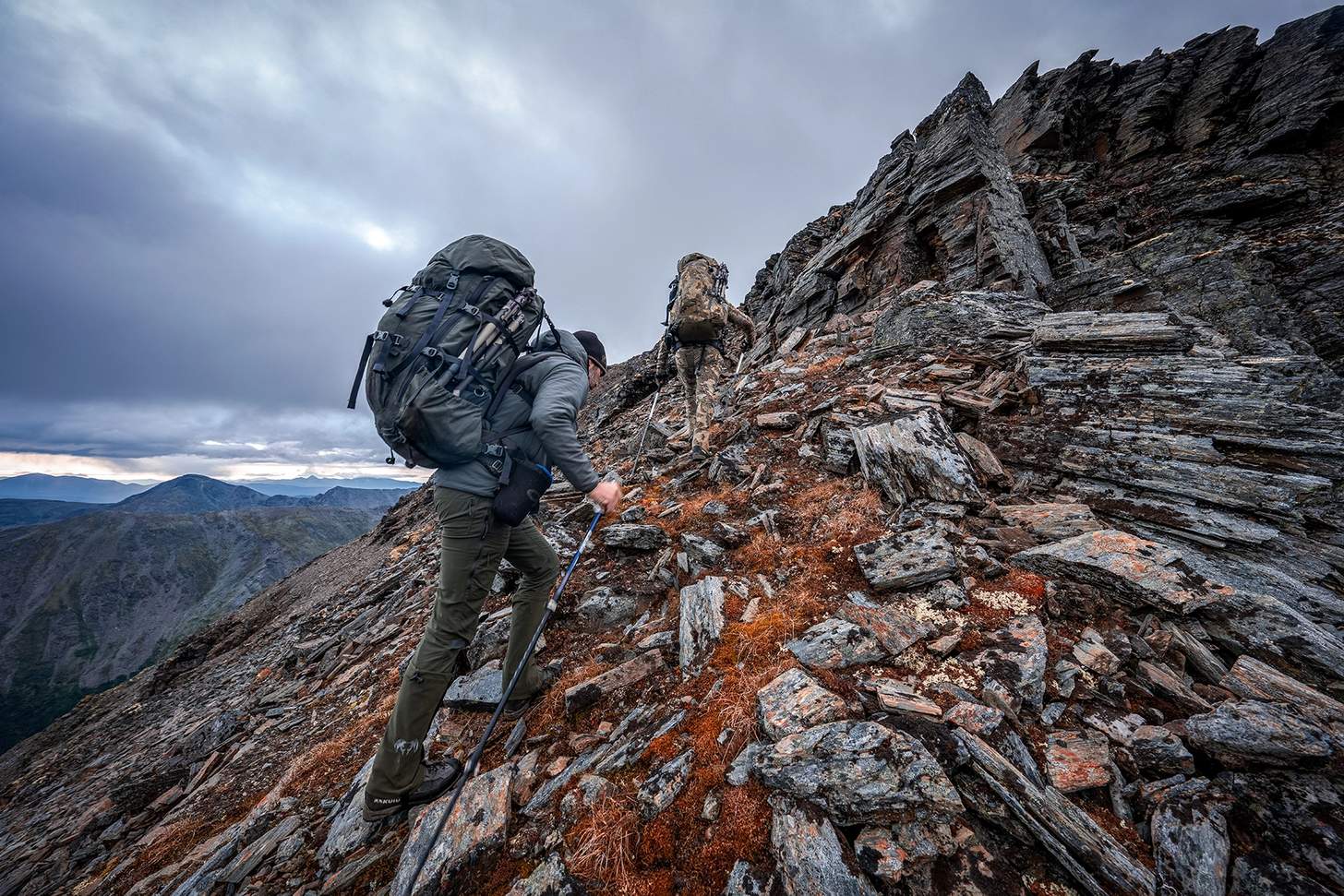 two hunters in kuiu gear climbing a steep rocky cliff