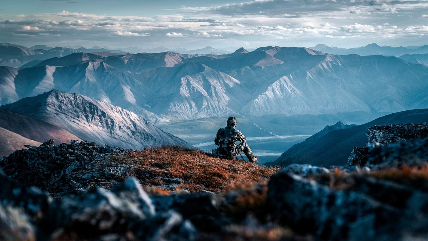 a hunter in kuiu gear sitting on a cliff