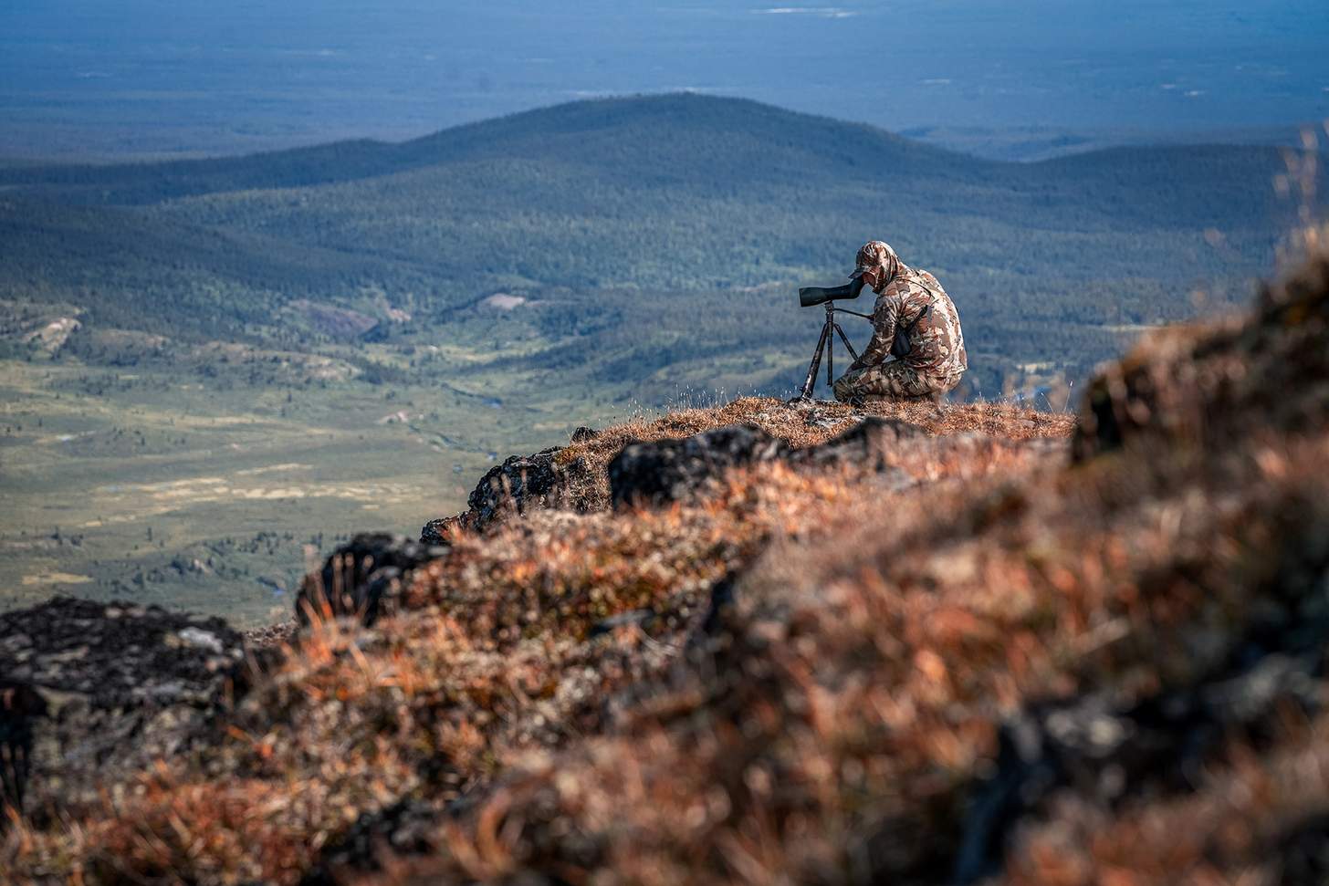 a hunter glassing on a cliff