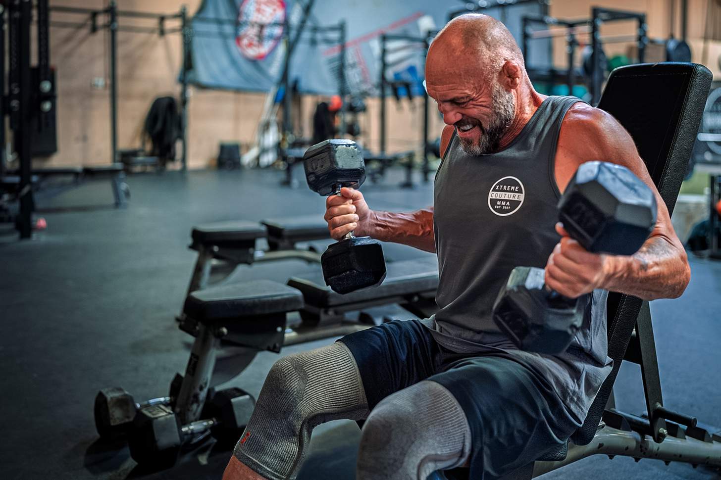 Randy Couture doing dumbbell curls in the gym