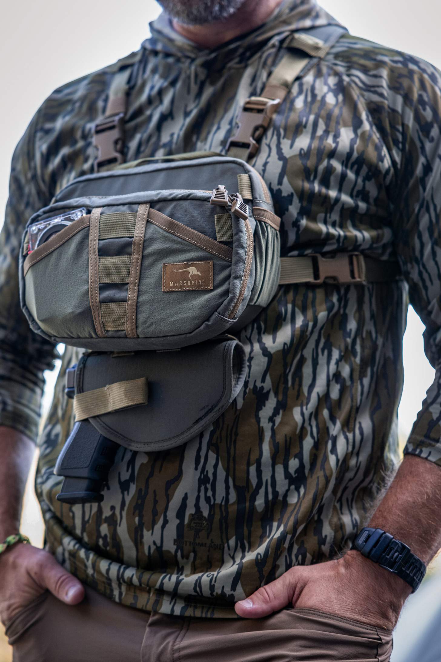 Born Primitive Apparel in Mossy Oak Bottomland shirt with Marsupial chestpack and pistol holster.