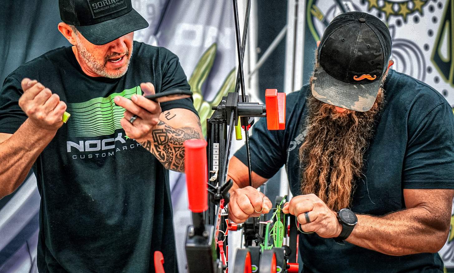 John Dudley tuning a bow on a press with another archer