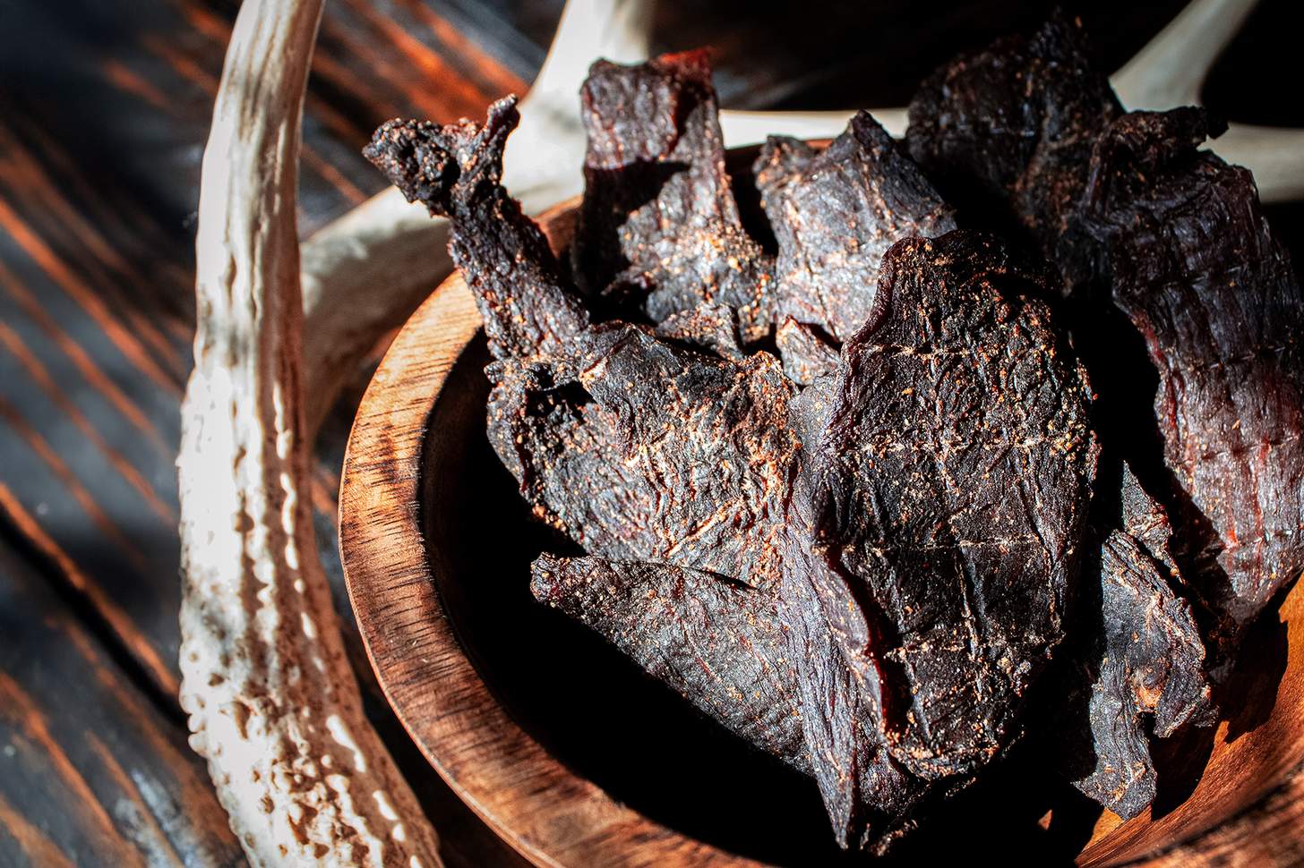 venison jerky in a wooden bowl with an antler