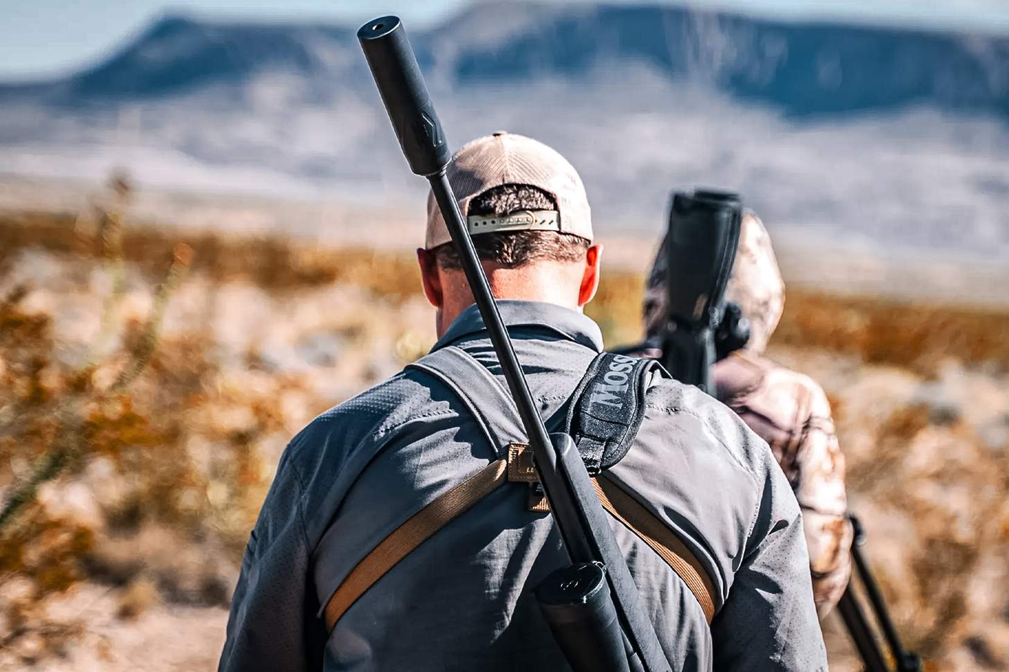 slung rifle with a suppressor on the barrel