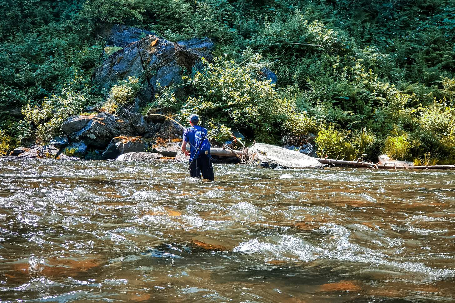 man fly fishing in a river