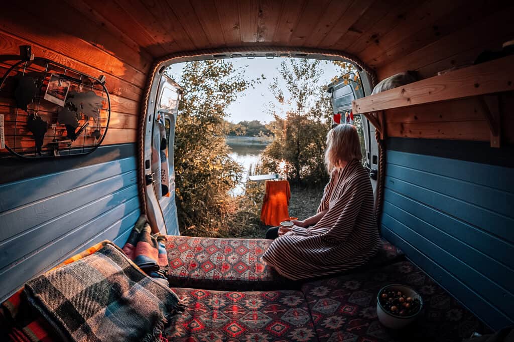 A woman looking out the rear door of a conversion van at nature