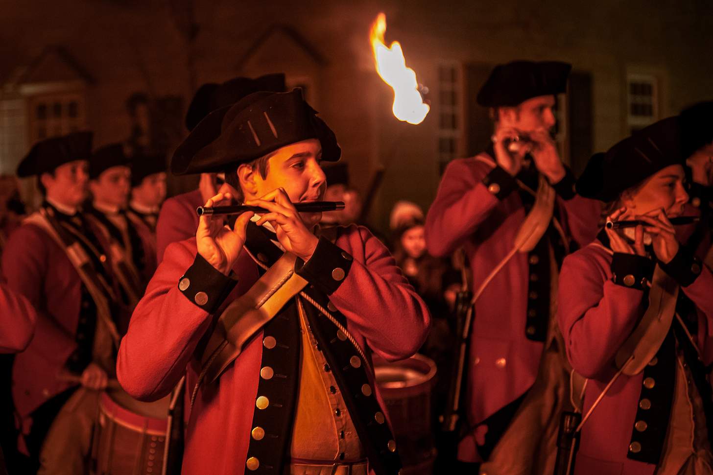 Red-coated fife and drum corps take part in the Illumination of the Taverns parade in Colonial Williamsburg. American Revolution musician re-enactors