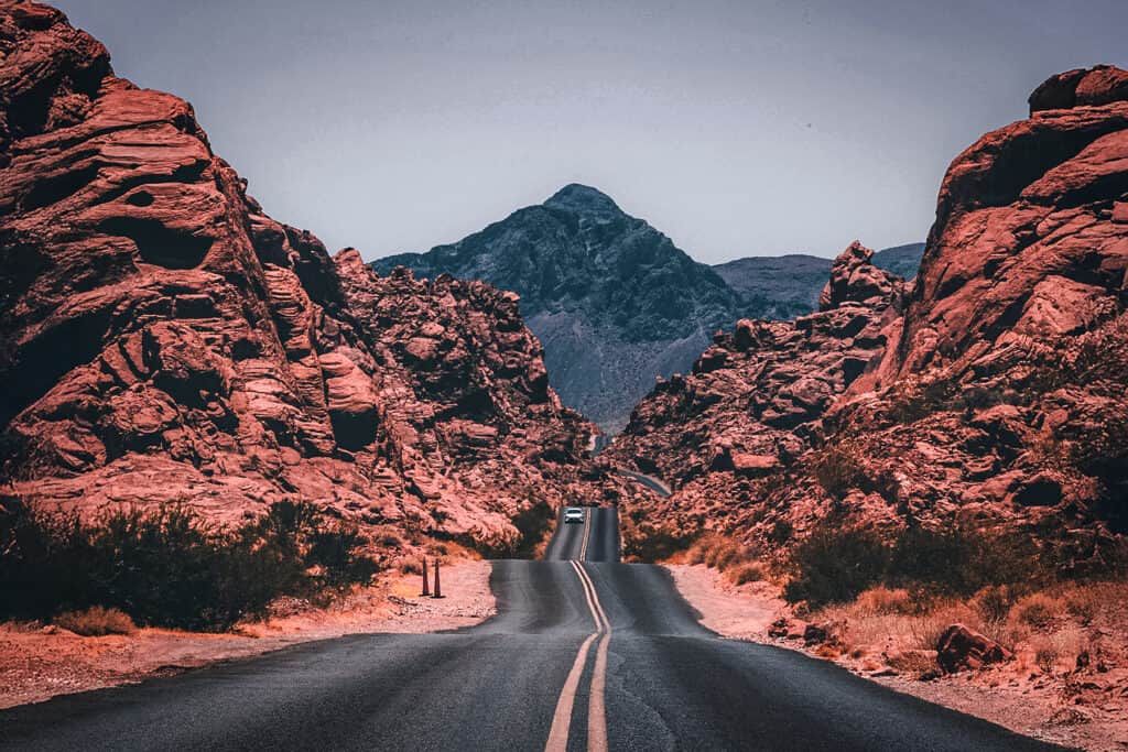 A van traveling down a secluded road in the rocky desert