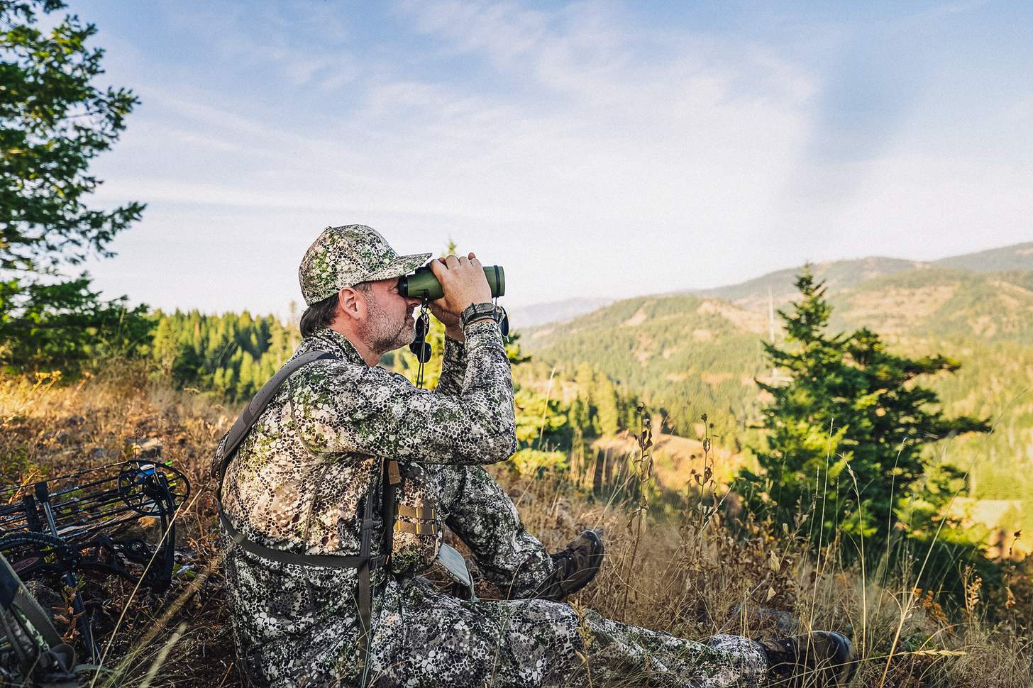 a bowhunter glassing a valley