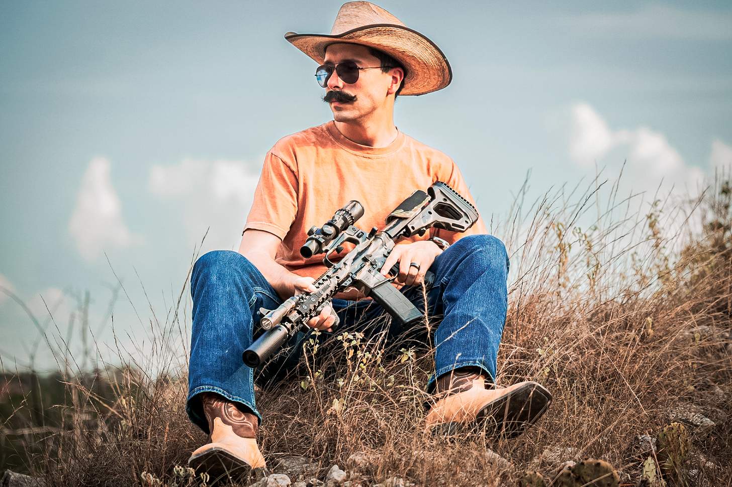 man in cowboy hat with a suppressed AR
