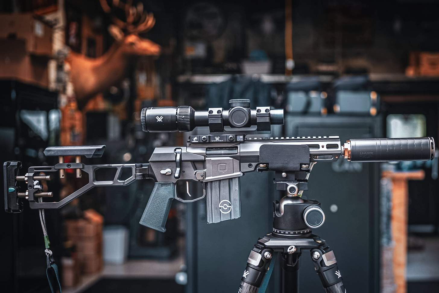 short barreled rifle with a suppressor and folding stock on a tripod